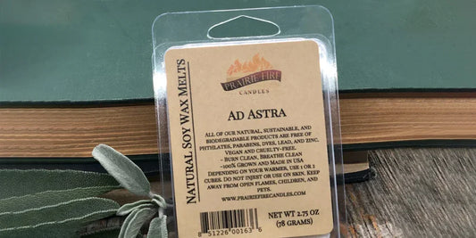 Natural soy wax melts labeled 'Ad Astra' in eco-friendly packaging on wooden table with books.