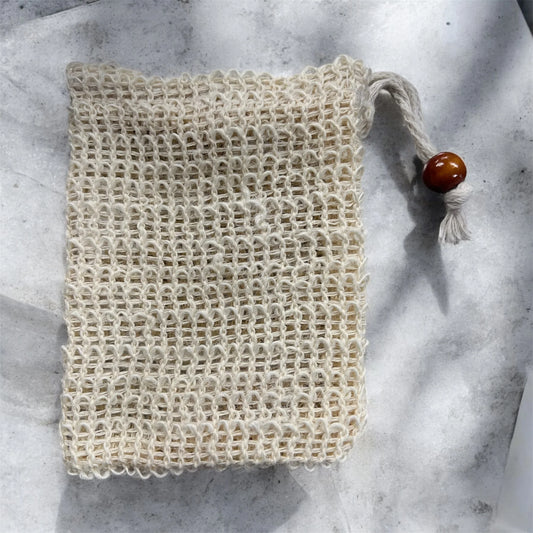 Natural fiber soap saver bag with drawstring and wooden bead on a light background
