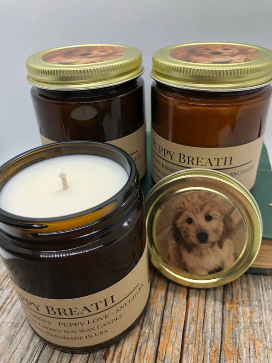 Puppy Breath soy wax candles in amber jars with gold lids, featuring puppy image stickers.