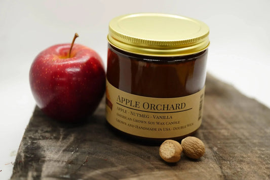 Apple Orchard soy candle in amber jar with apple and nutmeg on wooden surface