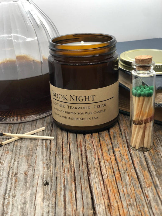 Book Night soy wax candle in amber jar on rustic wood table with matches and books