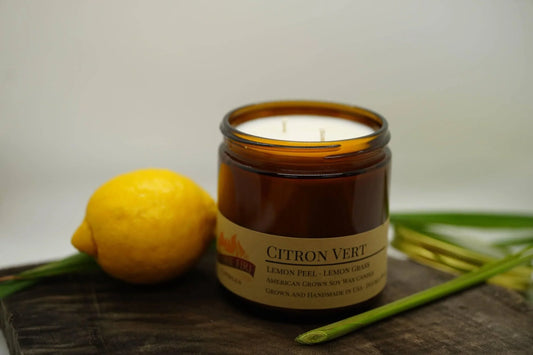 Citron Vert soy wax candle in amber jar with lemon and lemongrass on a wooden surface