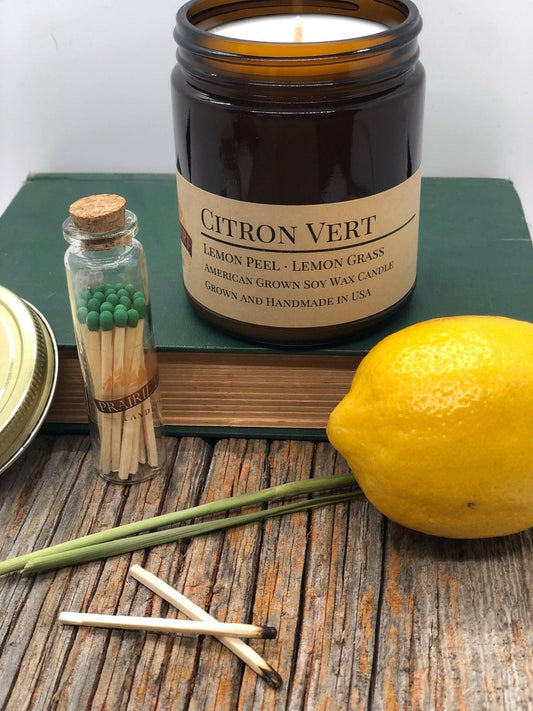 Soy wax citron vert candle in amber jar with lemon, lemongrass, matches on rustic wood table
