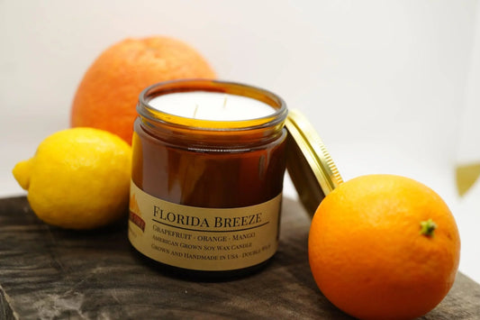Florida Breeze soy wax candle in amber jar with citrus fruits on wood surface