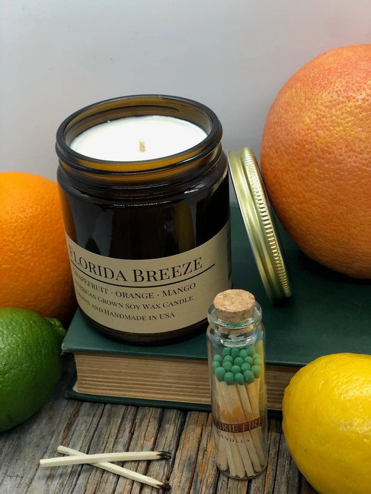 Florida Breeze soy wax candle in amber jar with citrus fruits and matches