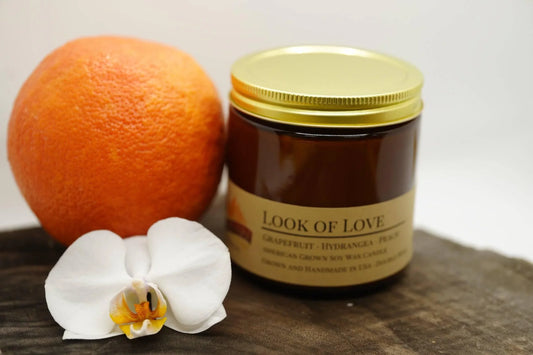 Amber glass soy wax candle labeled Look of Love with grapefruit and white orchid