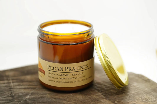 Pecan Pralines soy wax candle in amber jar with gold lid on wooden surface