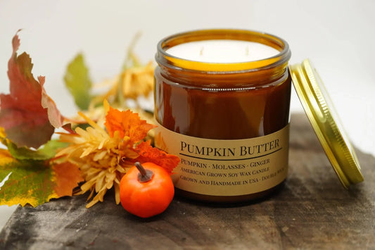 Pumpkin Butter soy wax candle in amber jar with autumn leaves and mini pumpkin on wood