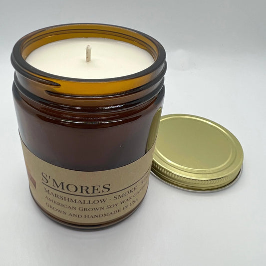 S'mores scented soy wax candle in amber glass jar with gold lid on white background