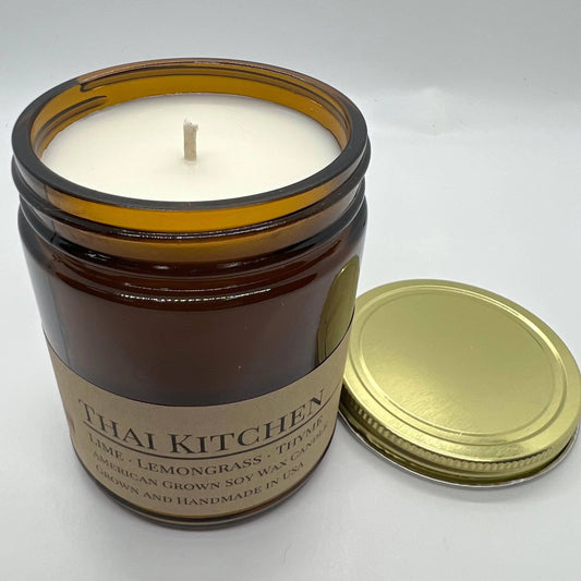 Scented soy wax candle in amber glass jar with cotton wick and gold lid, Thai Kitchen fragrance.