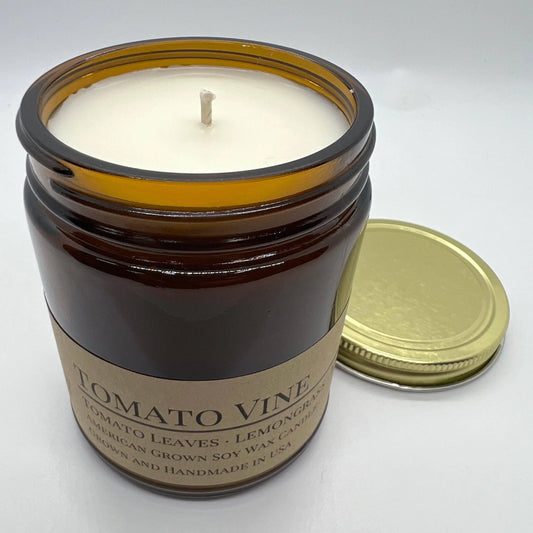 Soy wax candle in amber glass jar labeled Tomato Vine with gold lid on white background