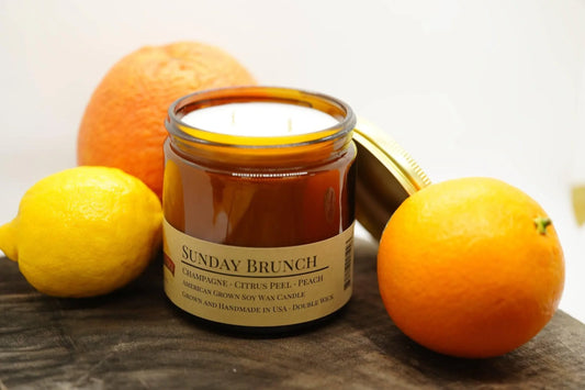 Sunday Brunch soy wax candle in amber jar with citrus fruits on wooden surface